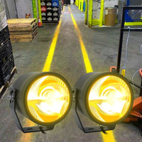 Overhead crane lighting creates blue safety paths on concrete