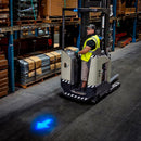 Worker driving floor vehicle with blue arrow light projection