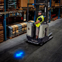 Worker driving floor vehicle with blue arrow light projection