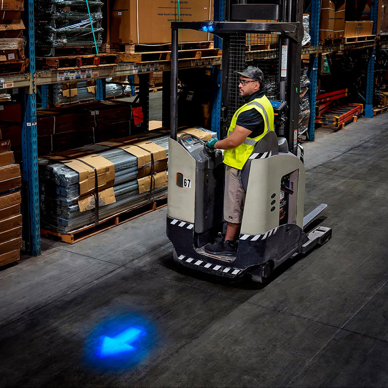 Worker driving floor vehicle with blue arrow light projection